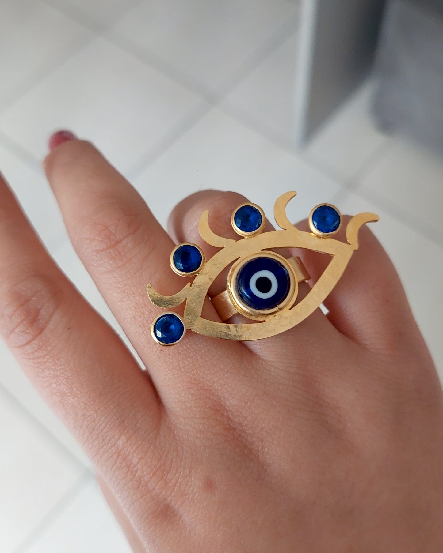 Gold ring with blue gemstones on a person's finger against a white background