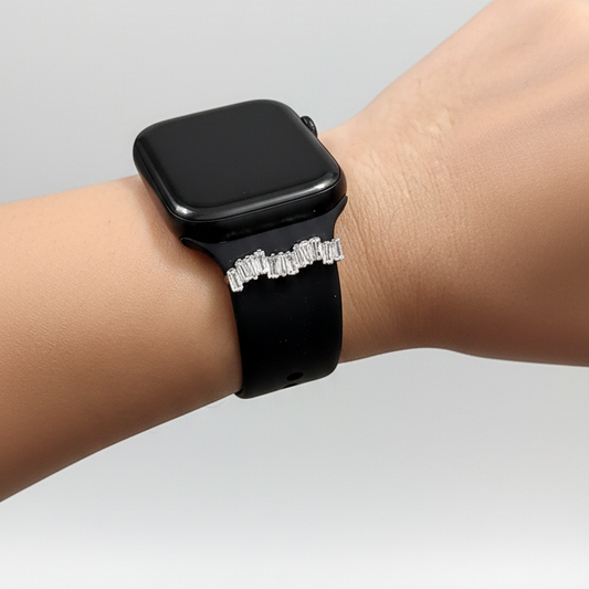 Black smartwatch on a wrist with baguette stones against a light gray background
