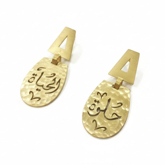 Gold earrings with Arabic text on a white background