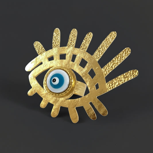Gold eye-shaped brooch with blue center on a white background
