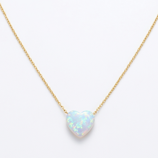Gold necklace with a heart-shaped opal pendant on a white background