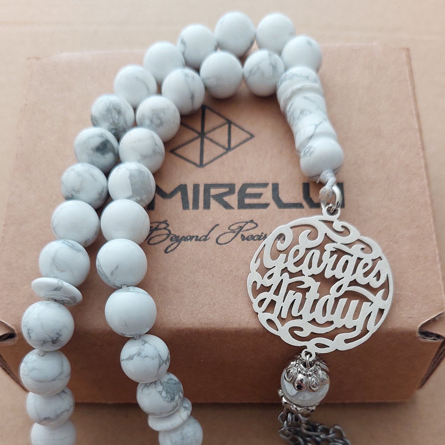 masbaha with white beads and customized name on a cardboard background