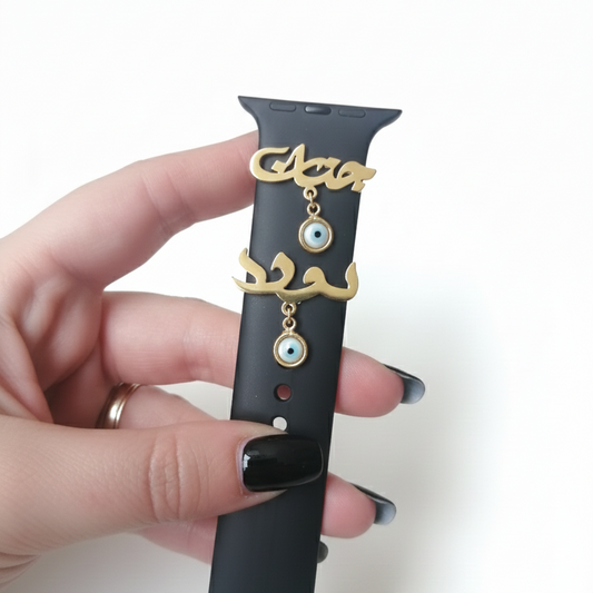 Black Apple Watch band with gold name with evil eye stone held by a hand on a white background