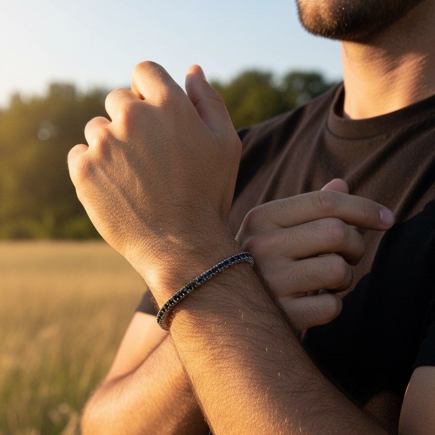 man wearing black stone tennis bracelet with a blurred nature background