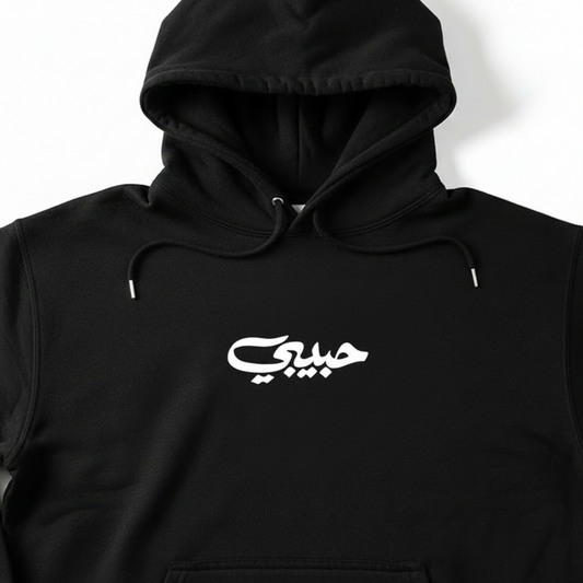 Black hoodie with a white habibi in arabic on a white background