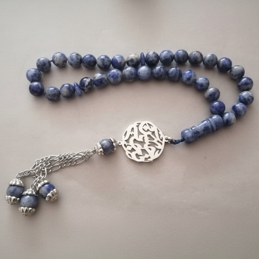 Blue beaded necklace with a silver clasp on a light gray background