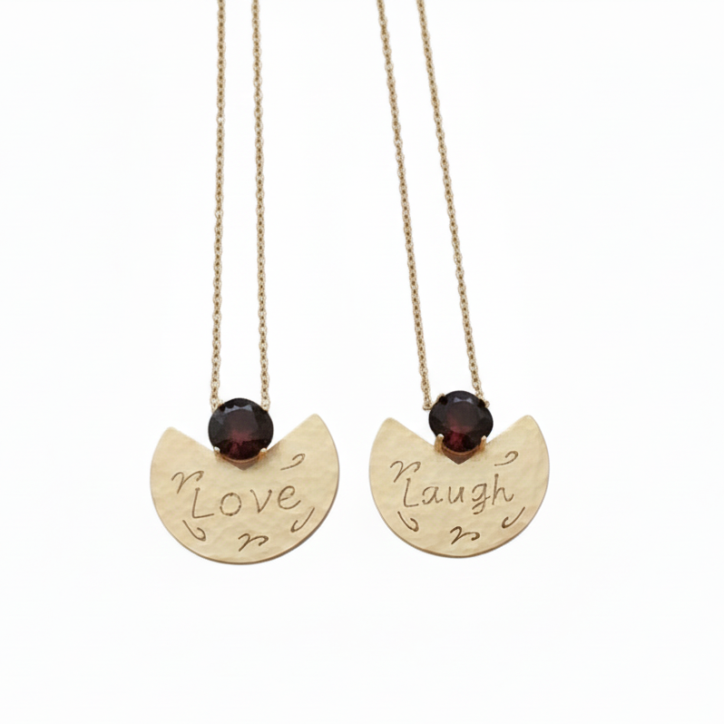 Two gold necklaces with engraved words 'Love' and 'Laugh' on a white background
