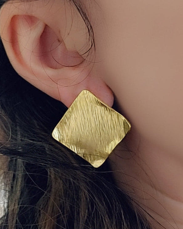 Gold earring worn by a person with dark hair.