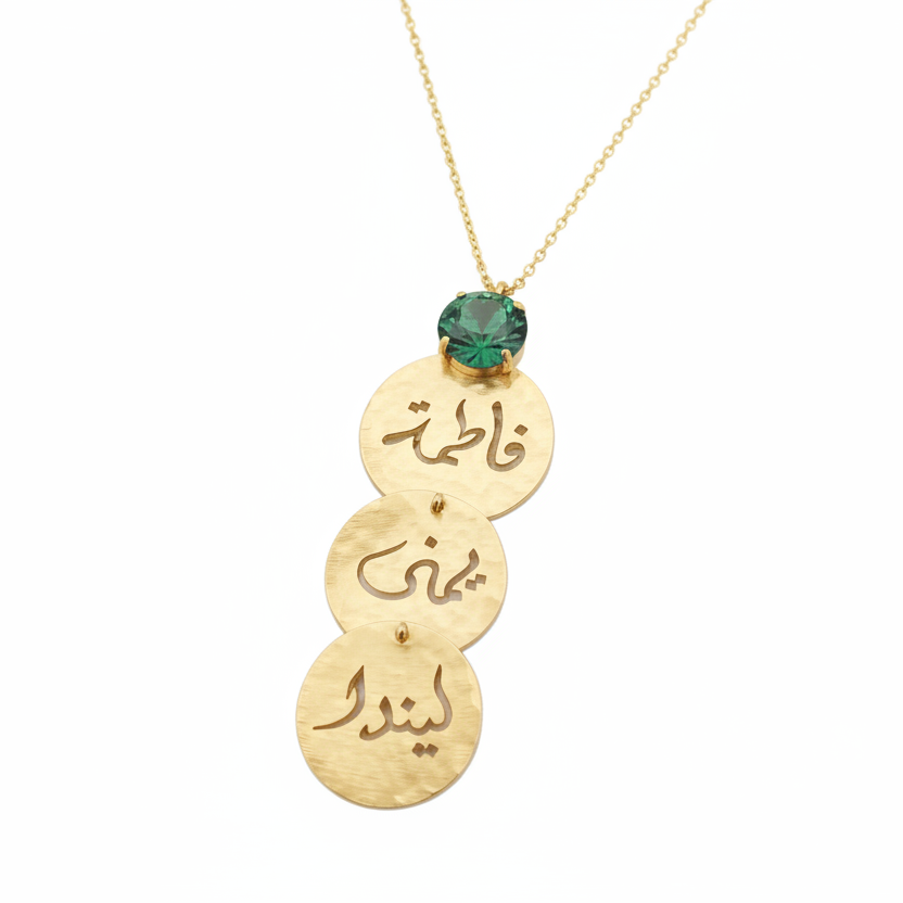 A gold pendant necklace featuring three stacked hammered circular discs with Arabic calligraphy, a small erinite swarovski at the top, and a delicate gold chain.
