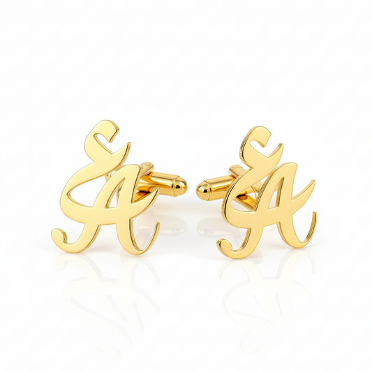 Gold cufflinks with a mix of english and arabic letter inititals design on a white background