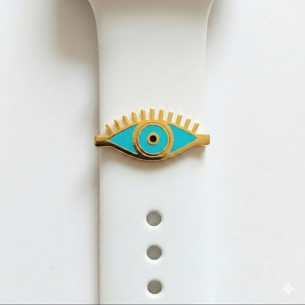 Eye-shaped watch charmwith turquoise center and gold outline on a white smart watch band