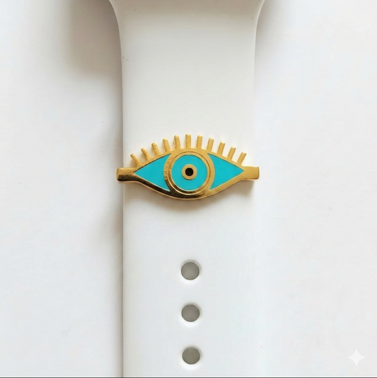 Eye-shaped watch charmwith turquoise center and gold outline on a white smart watch band