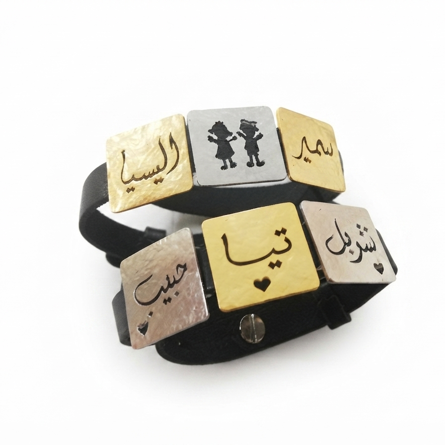 A black leather bracelet with five rectangular metal nameplates in gold and silver, featuring Arabic calligraphy and a small silver heart, shown on a white background.