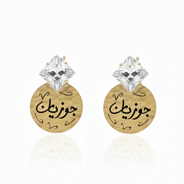 Gold earrings with Arabic text and clear square swarovski crystal on a white background