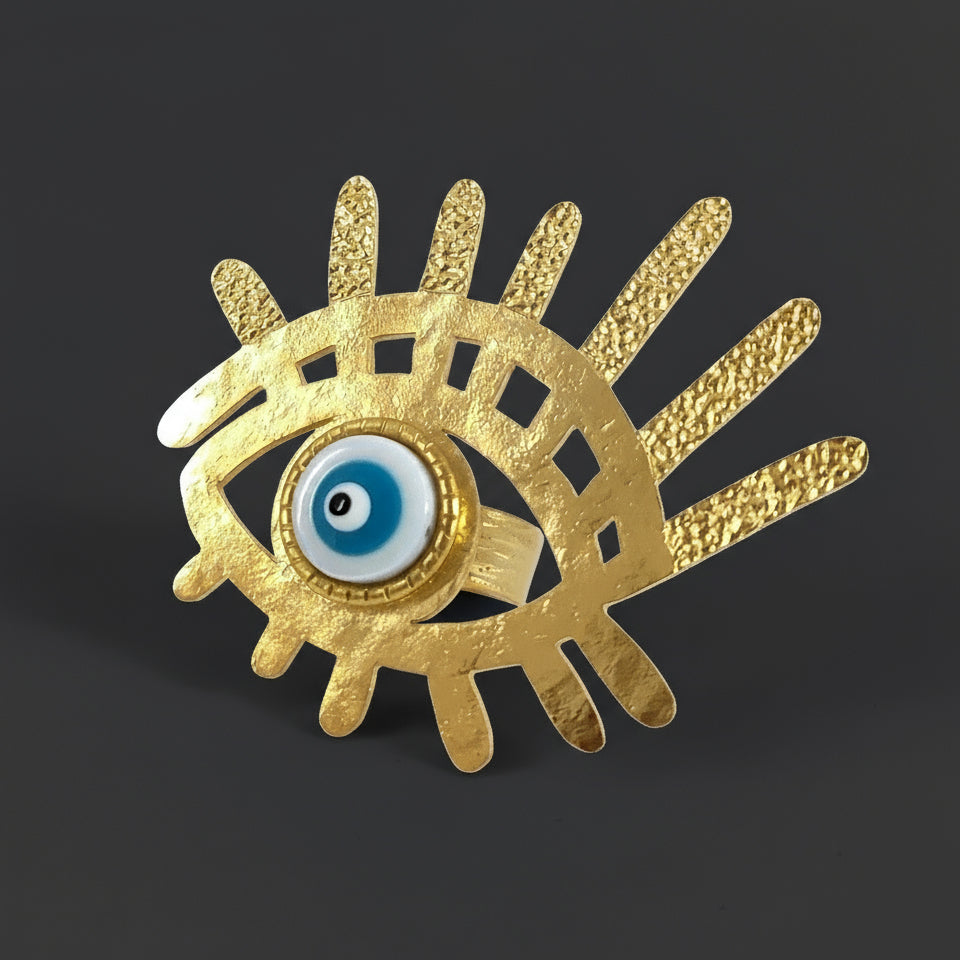 Gold eye-shaped brooch with blue center on a white background