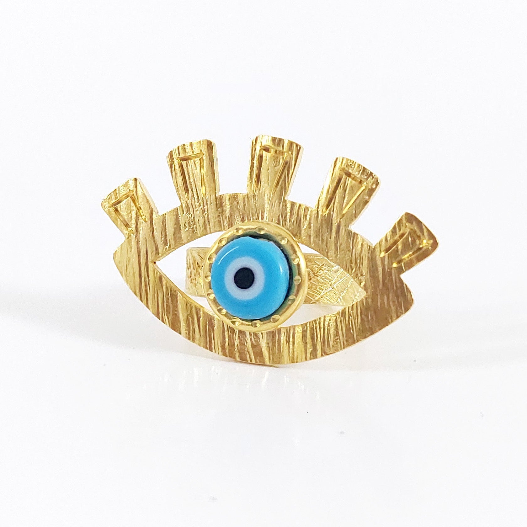 Gold eye-shaped brooch with a blue center on a white background