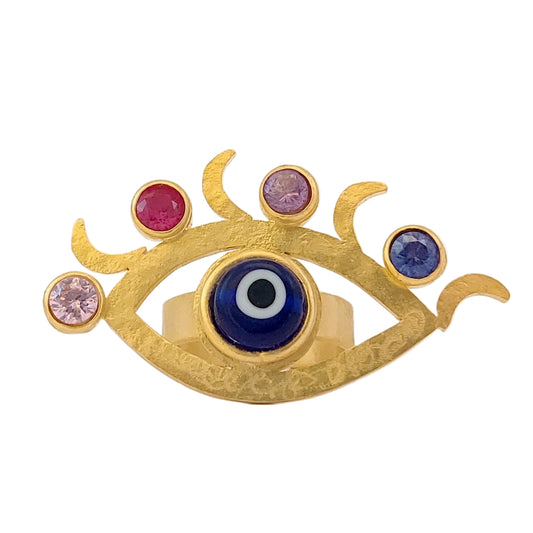 Gold ring with eye design and colored gemstones on a white background