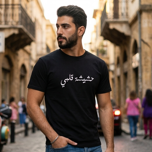 Man wearing a black t-shirt with Arabic text on a street in an urban setting