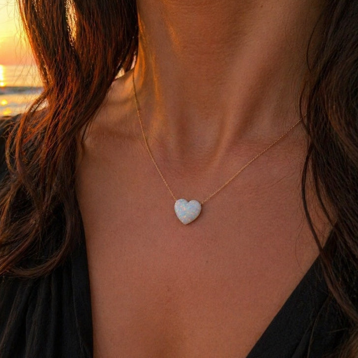Heart-shaped opal necklace worn by a person with a sunset background
