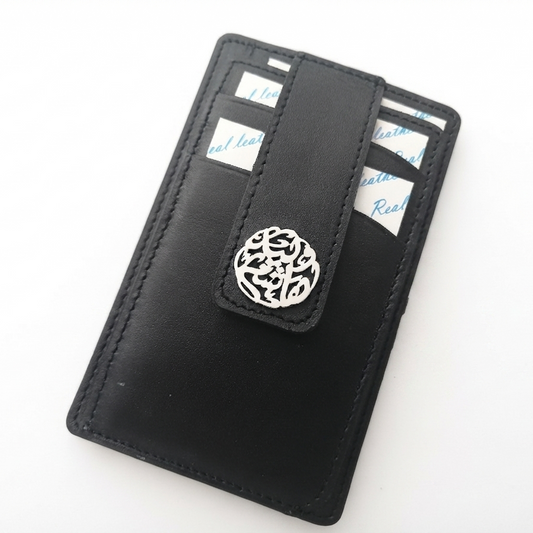A black leather slim card holder wallet with a snap-button closure and a silver arabic calligraphy, shown on a plain white background.