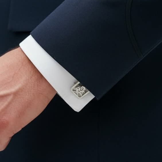 a man wearing a suit and showcasing his cedar silver cufflinks