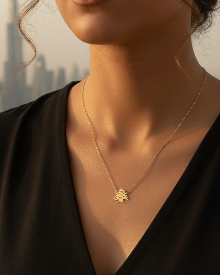 Gold necklace with a leaf pendant worn by a person against a blurred background