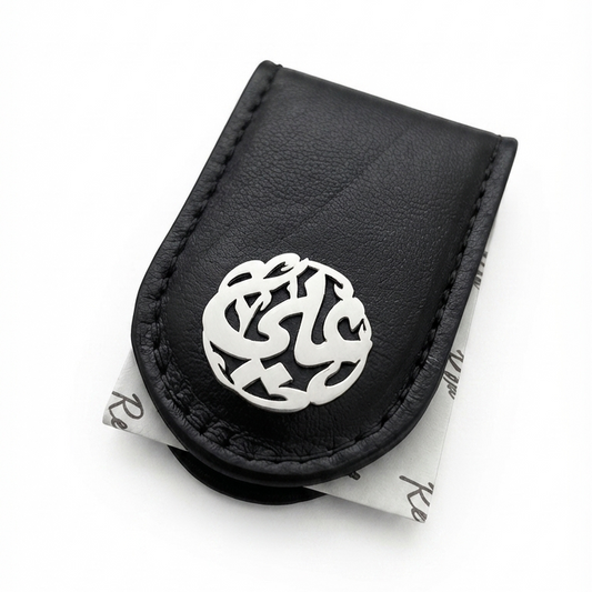A black leather money clip featuring a silver-tone metal circular clasp with intricate Arabic calligraphy, displayed on a clean white background.