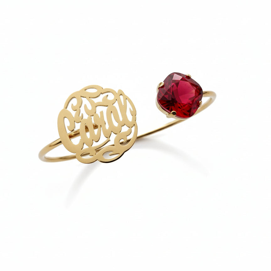 Gold bracelet with intricate design and red gemstone on a white background