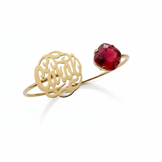 Gold bracelet with intricate design and red gemstone on a white background