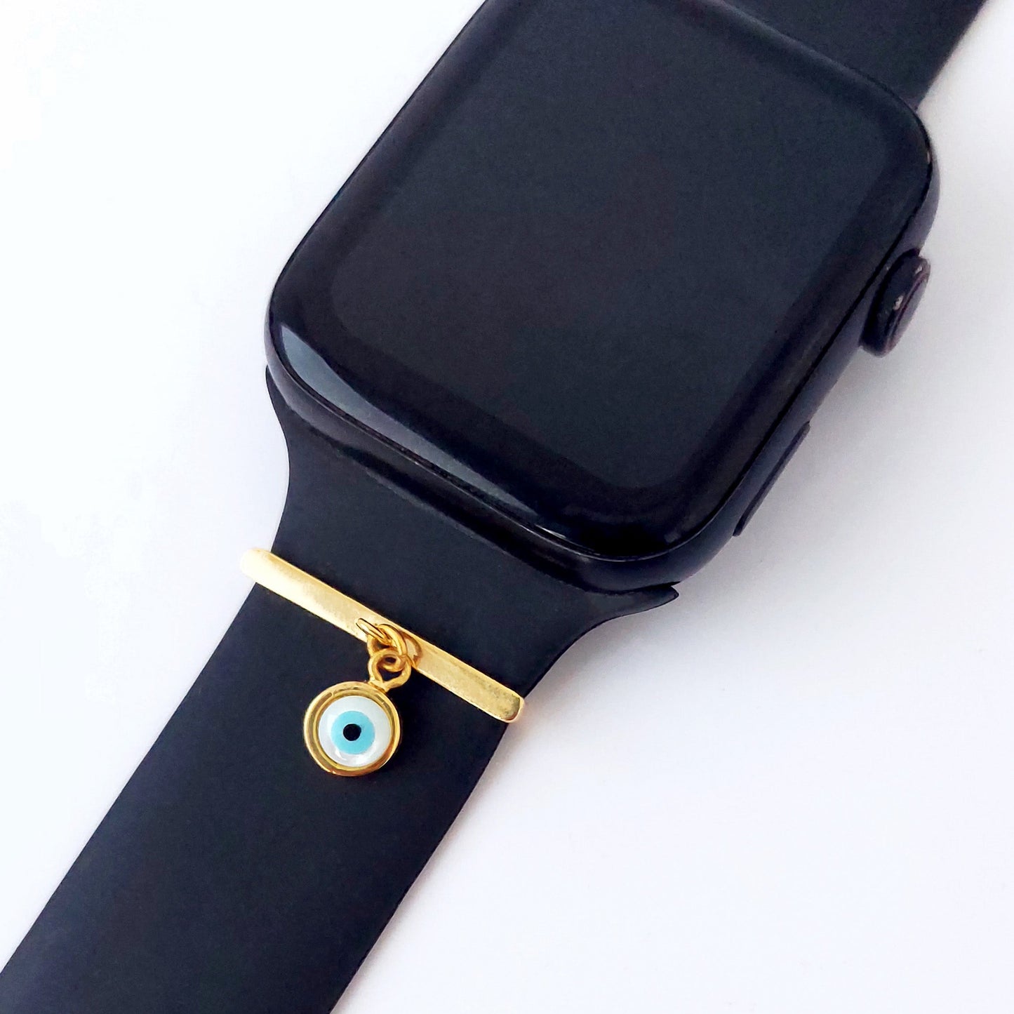 Black smartwatch with a gold charm and evil eye smart watch band add on on a white background