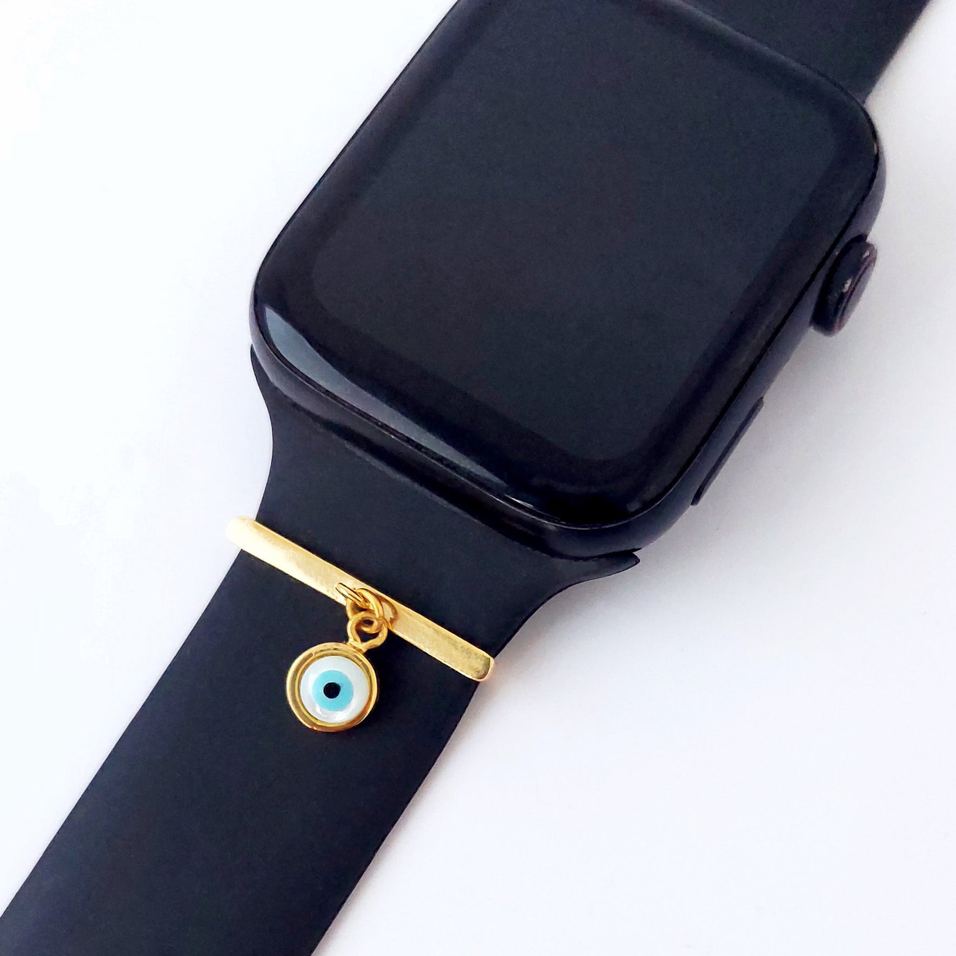 Black smartwatch with a gold charm and evil eye smart watch band add on on a white background