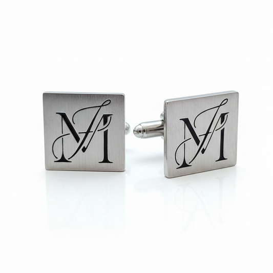 Pair of silver cufflinks with monogram design on a white background
