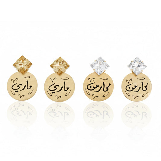 Pair of gold earrings with Arabic text on a white background