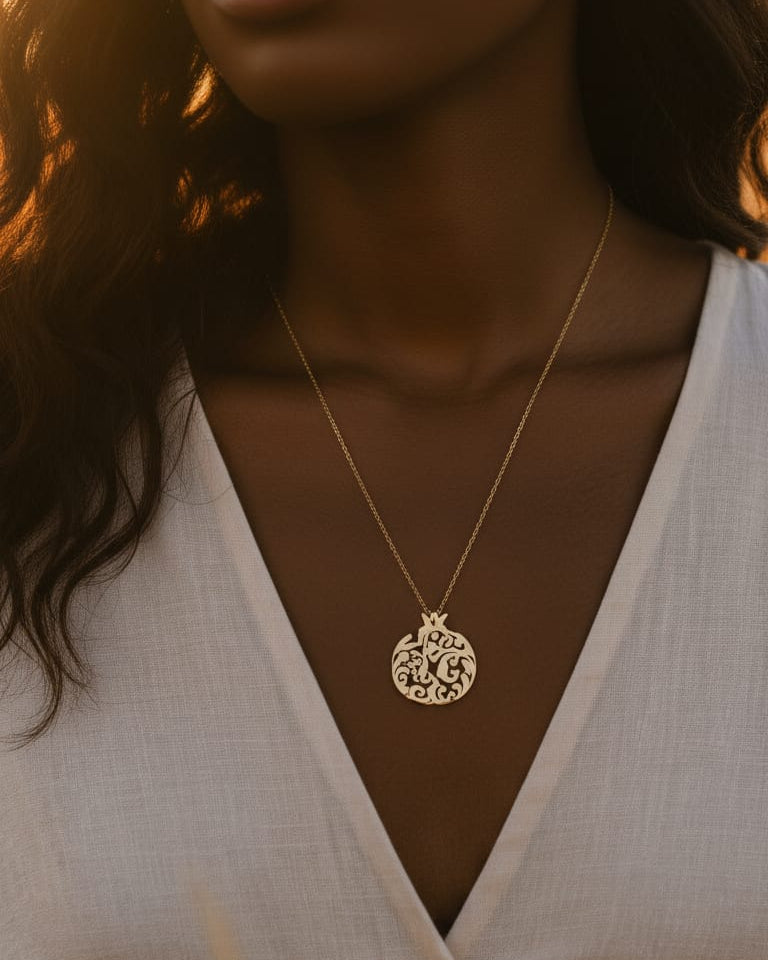 Close-up of a person wearing a gold necklace with a circular pendant against a neutral background